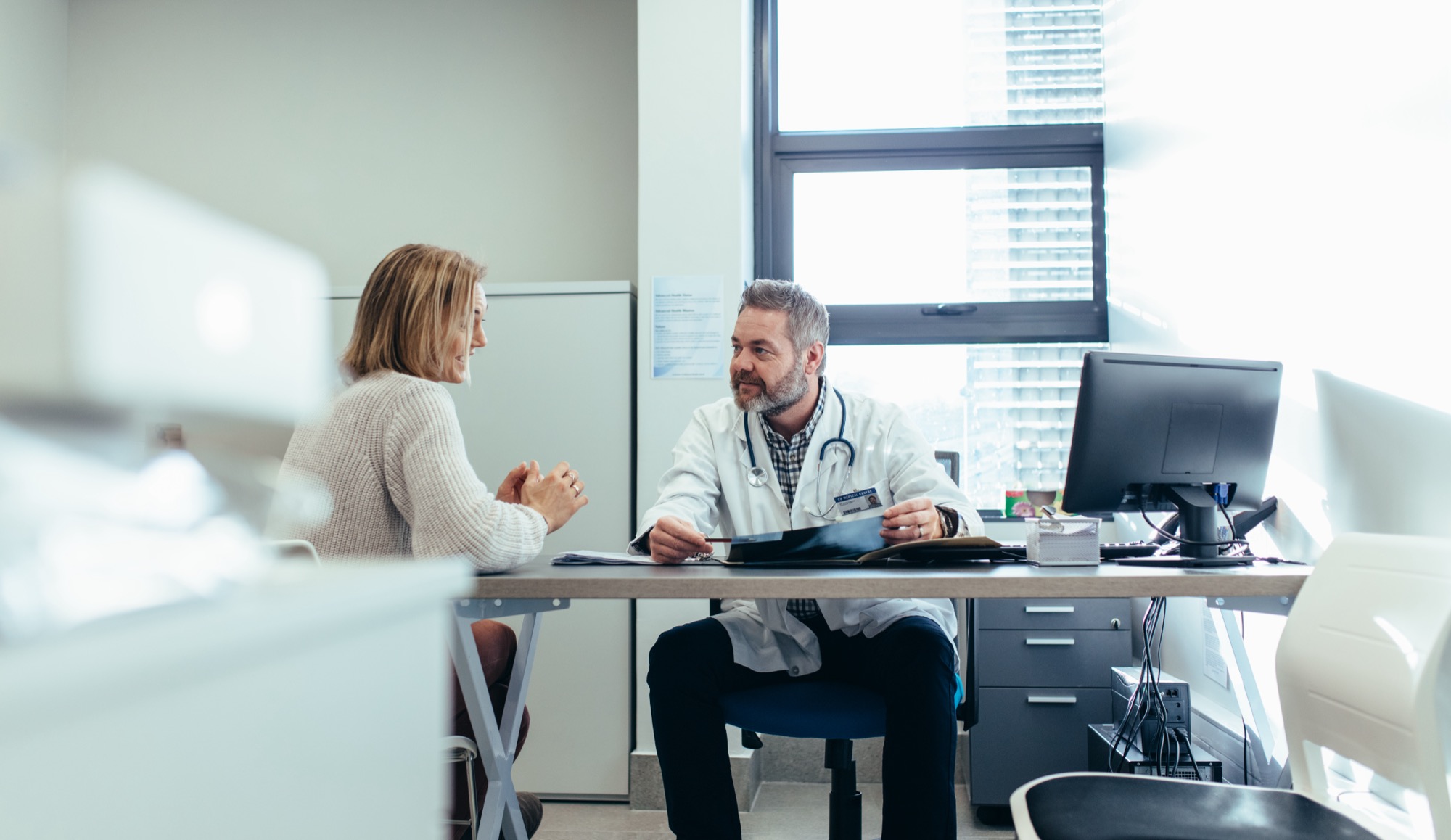 Medical specialist discussing with female patient in his clinic.